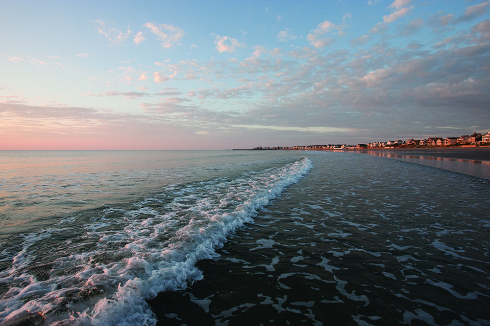 a view of the ocean and beach at sunset