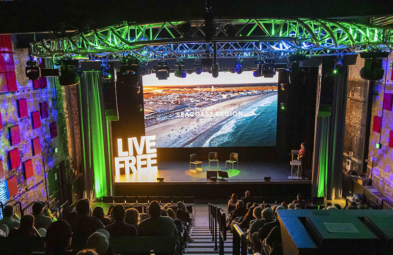 a view of a stage with stadium seating and a lit up "LIVE FREE" display.