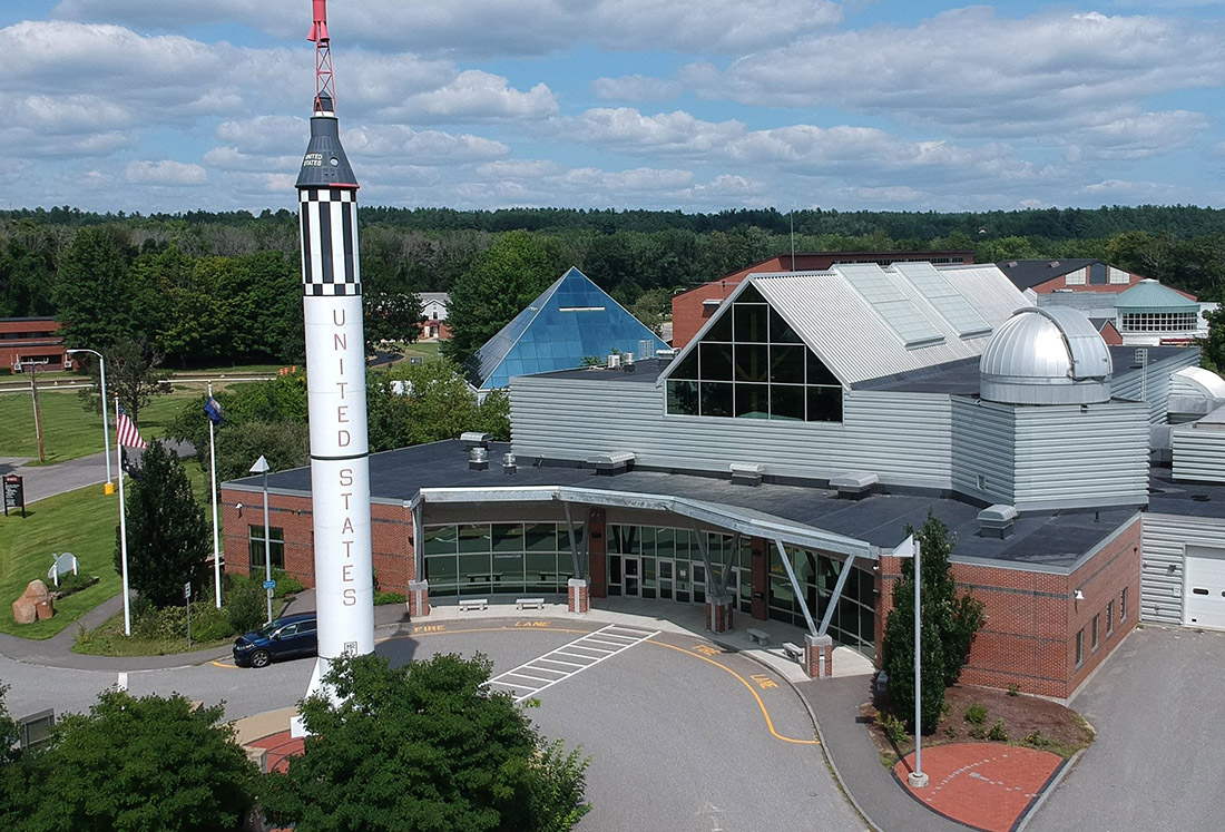 an aerial view of a science center with giant model rocket out front