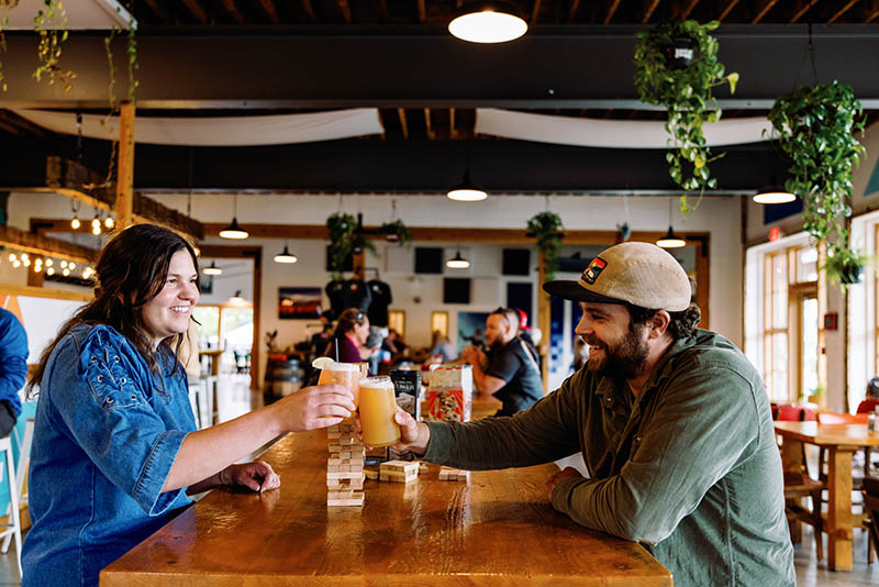 a man and woman sitting at a table with beers
