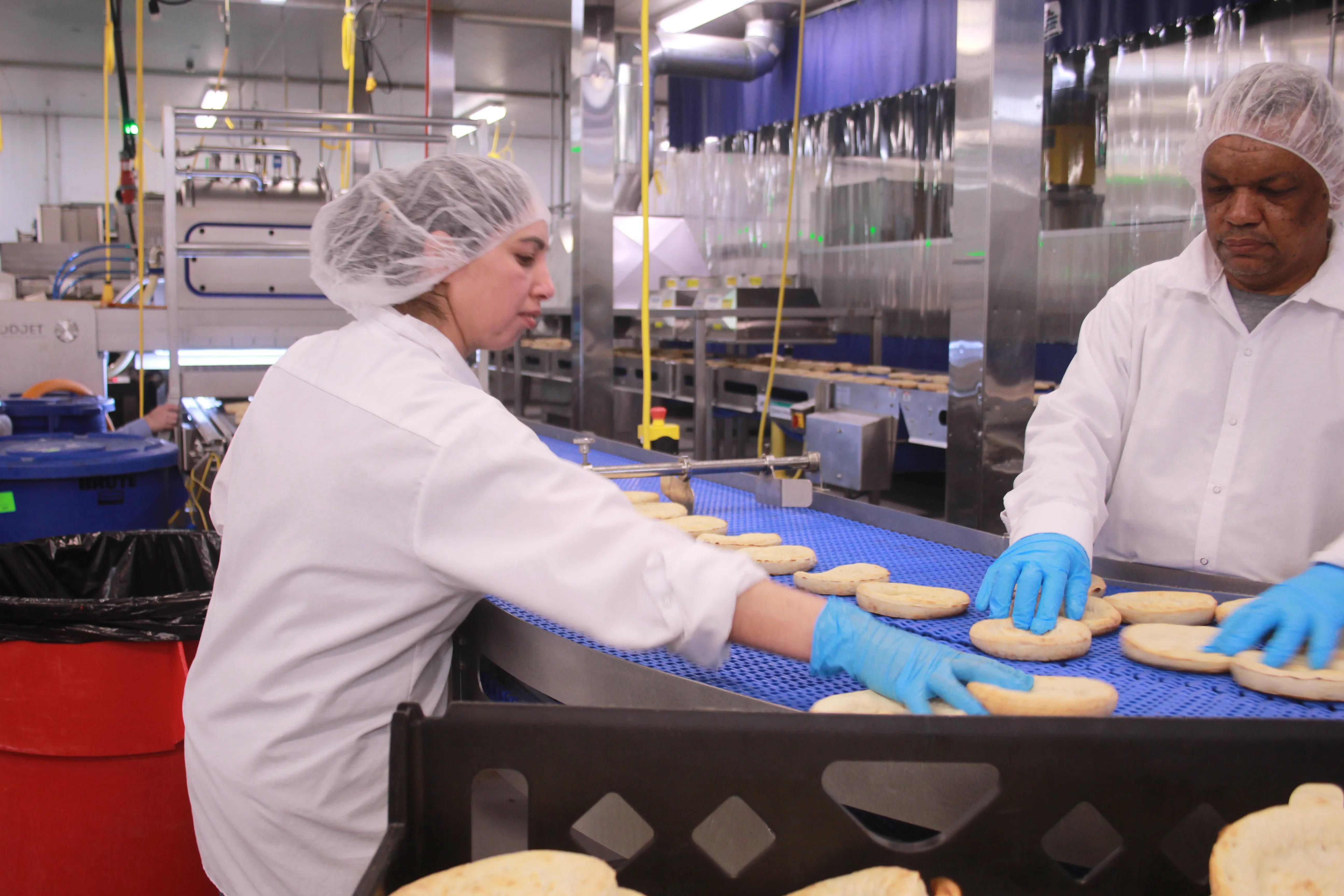 Two workers preparing food on a line belt