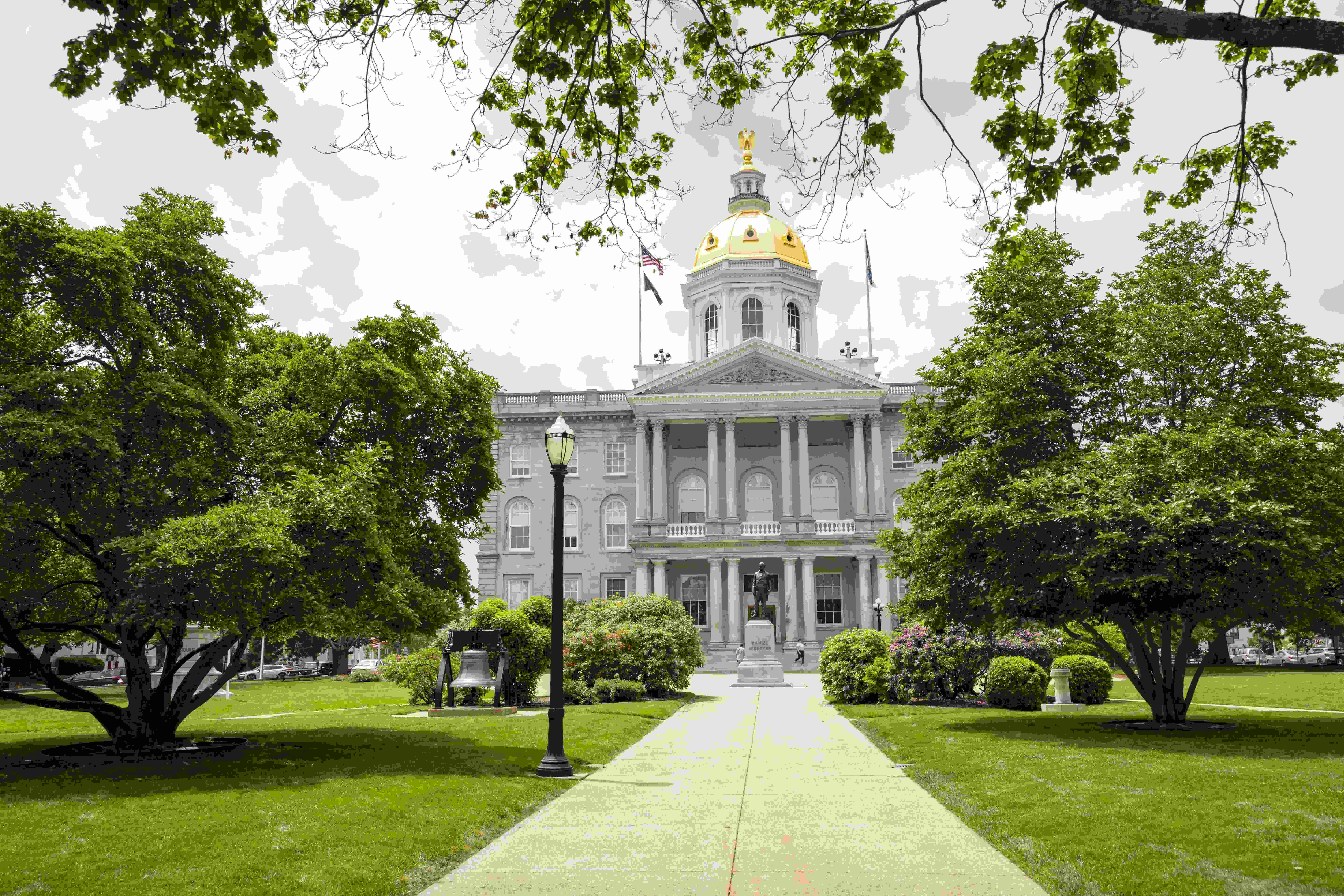 the NH statehouse with green lawn and trees surrounding