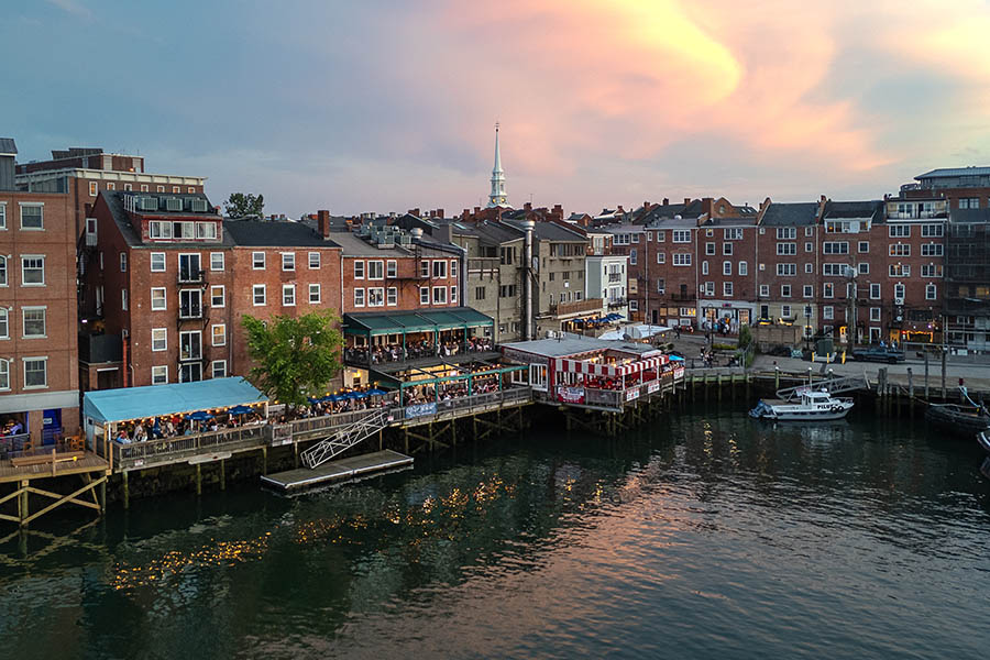 an aerial view of water and brick buildings, with a lit up boardwalk