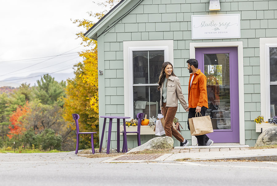 a couple exiting a store with shopping bags in fall