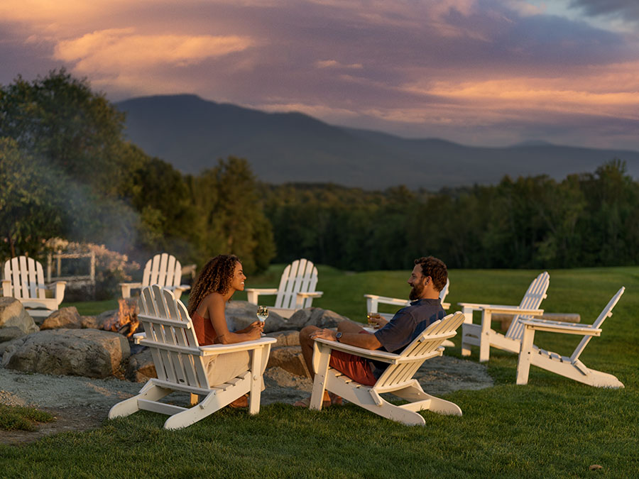 a couple sitting by a bonfire at sunset