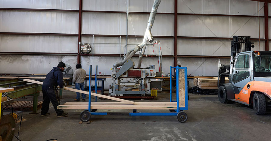 an arm lifting wooden boards in a warehouse