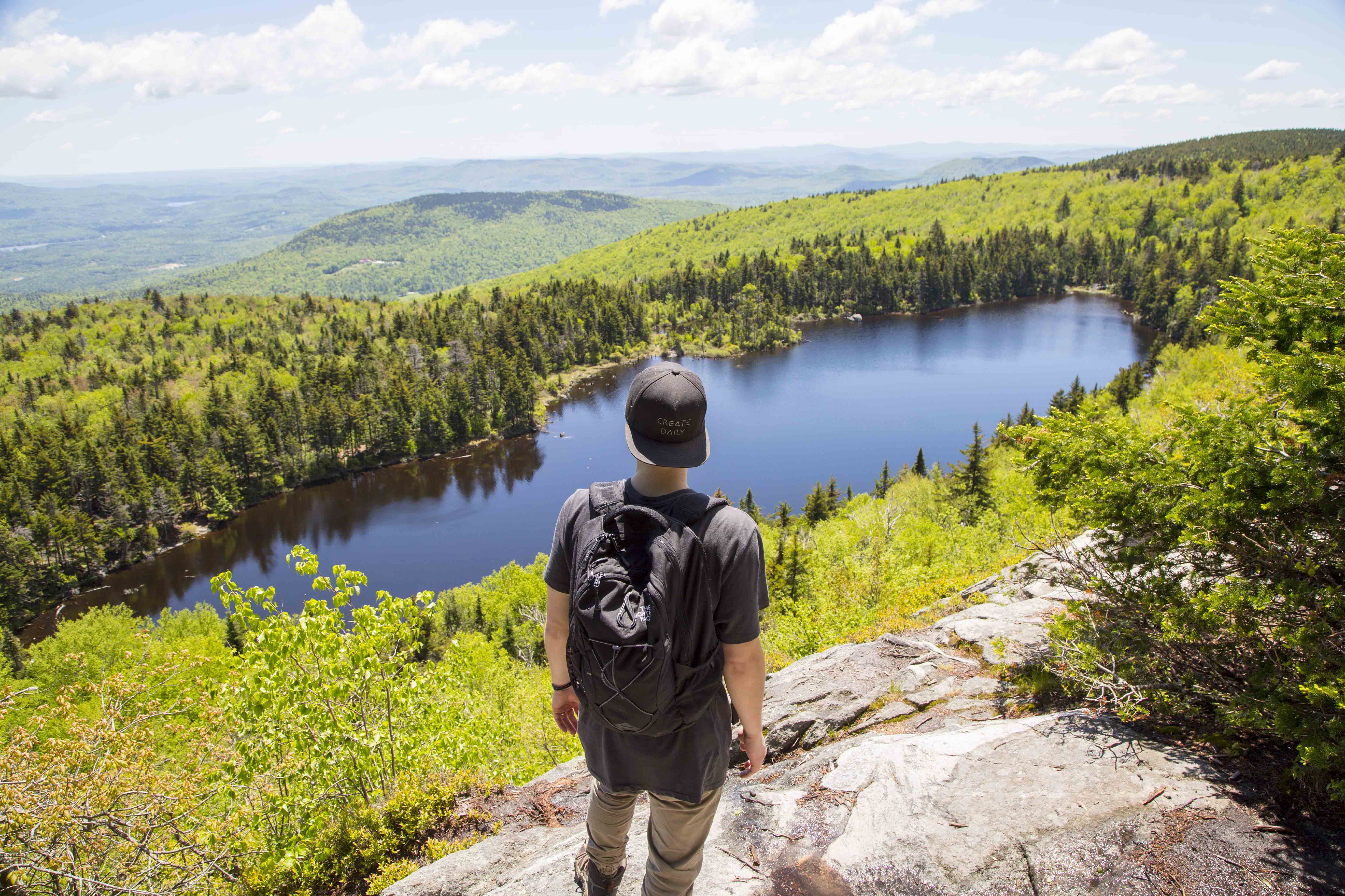 a hiker looking at a view of a lake with a backpack on