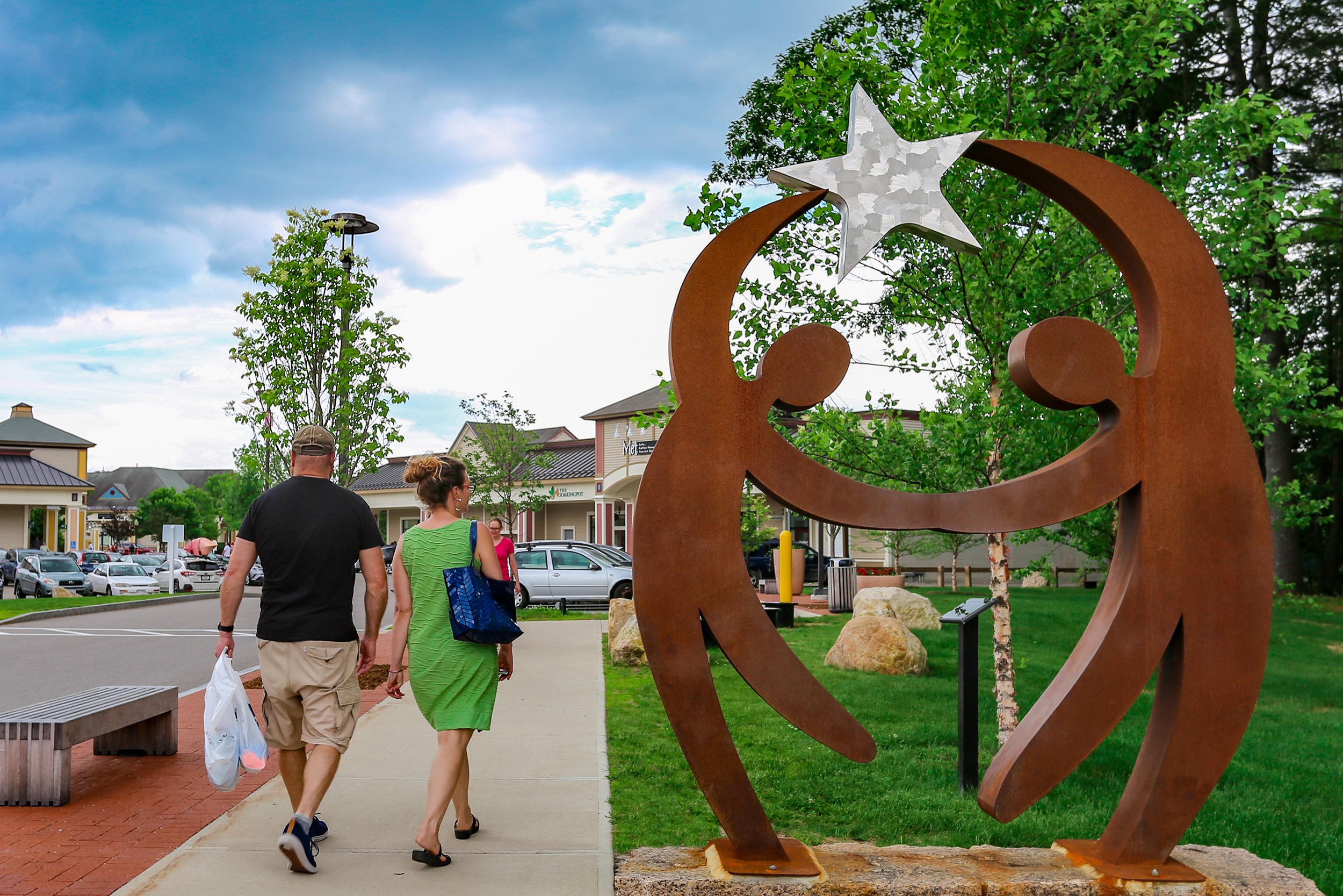 Shoppers stroll by one of a dozen pieces of public art at Settlers Green.