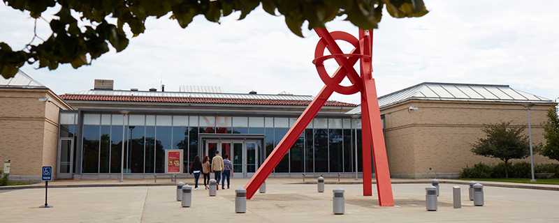 A group of people entering the Currier Museum, with red sculpture outside