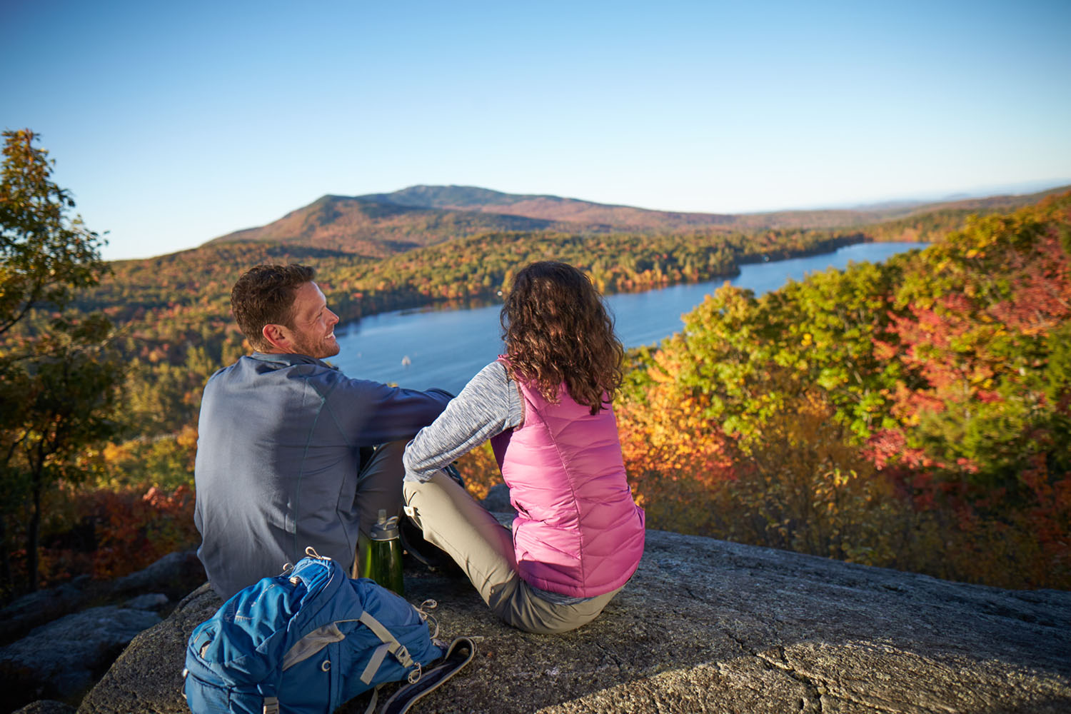 A couple looking out at the foliage on top of a summit