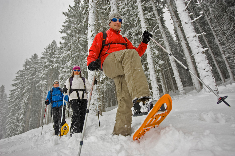 Three people snowshoeing through the snow. 