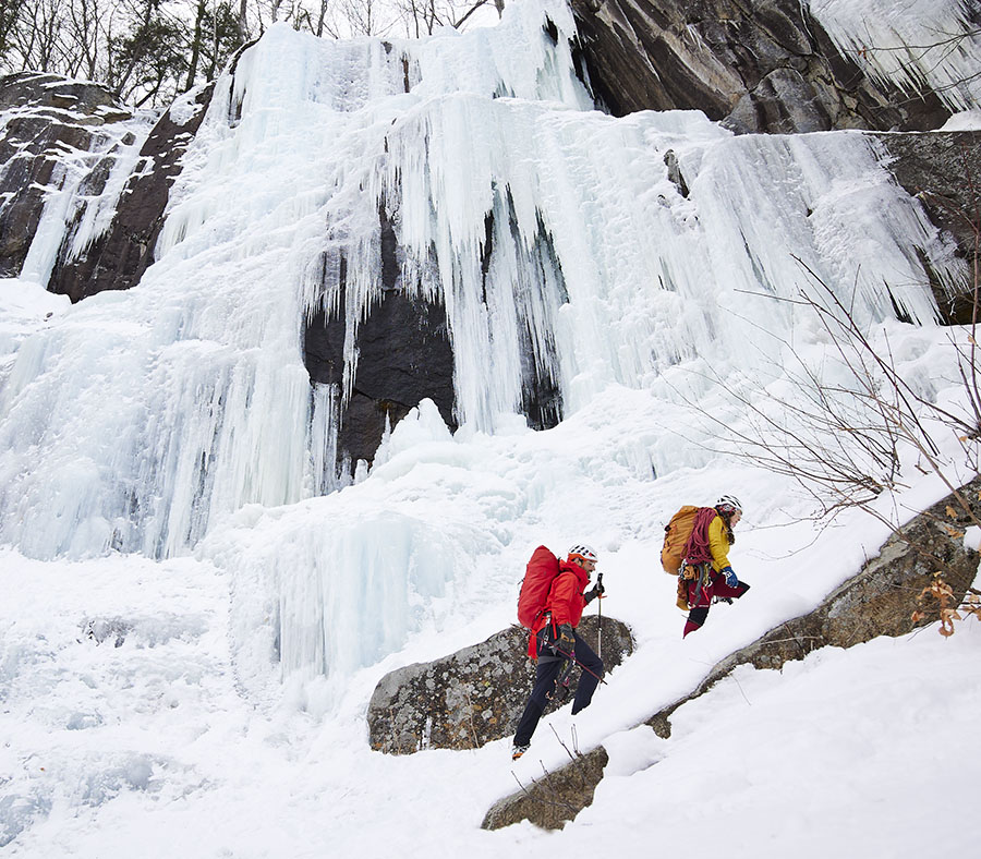 two ice climbers next to an icy cliff