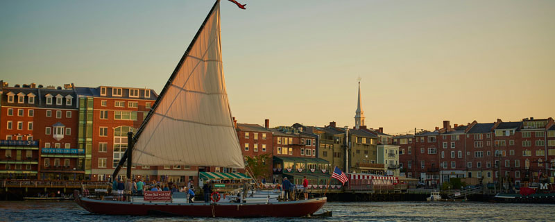 A gundalow sail boat against the Portsmouth skyline