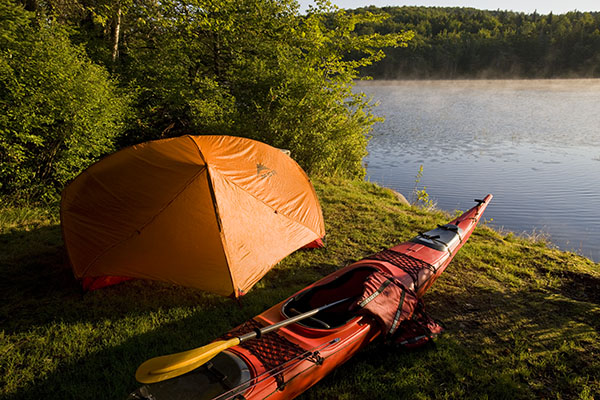 a tent and kayak by the river
